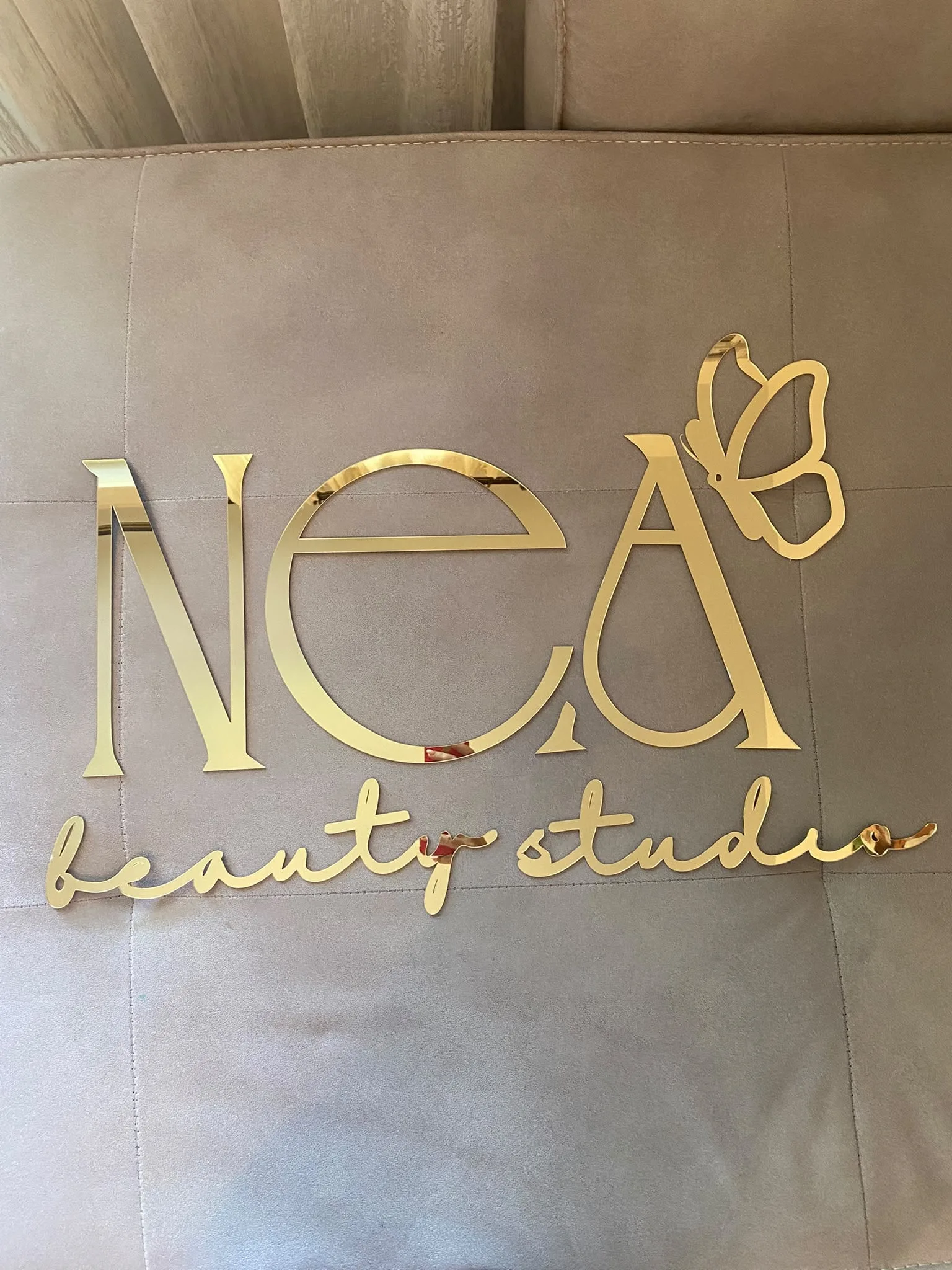 Logotip „NEA beauty studio“ od zlatnog pleksiglasa za salon lepote