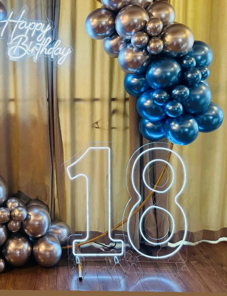 Neonski broj 18 od providnog pleksiglasa i neonski natpis „Happy Birthday“, uz luk od balona