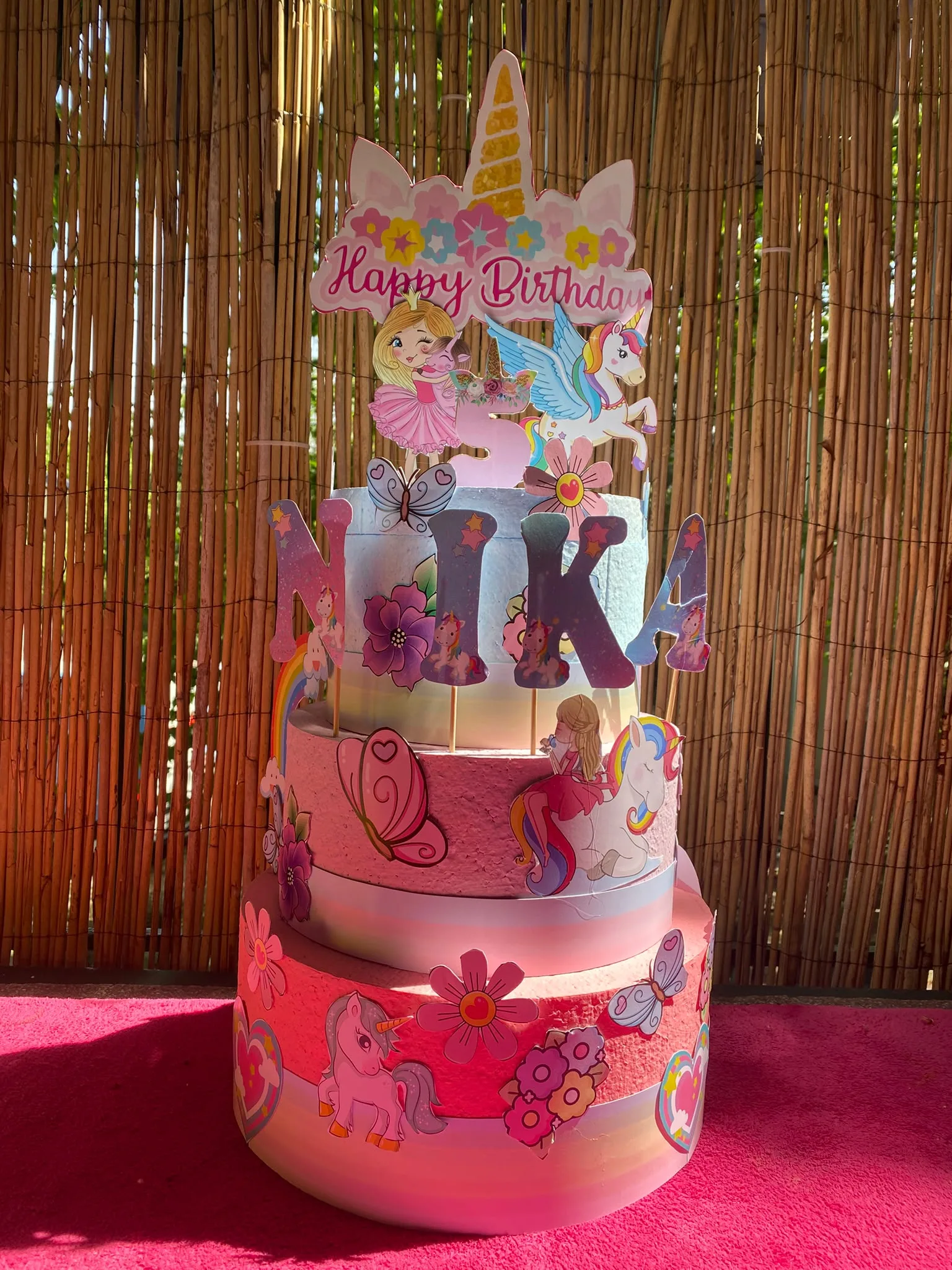 Torta od stiropora na tri sprata sa jednorogom i imenom „Nika“, u roze tonovima